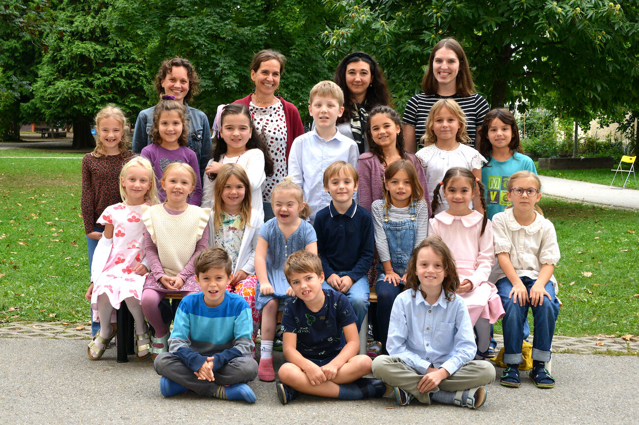 Eine Gruppe von Kindern und vier Erwachsenen posieren im Freien für ein Klassenfoto.