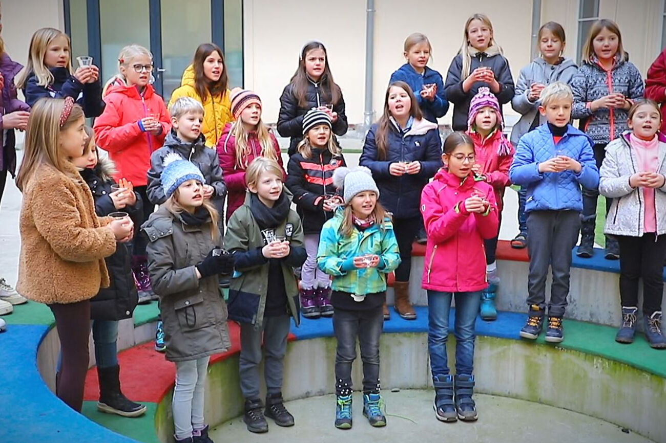 Eine Kindergruppe steht formiert im Halbkreis und gibt ein Lied zum Besten.