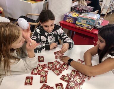 Drei Mädchen spielen auf einem Tisch das Spiel "Eier-Matsch".