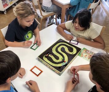 Vier Kinder spielen an einem Tisch das Spiel Kakerlakak.