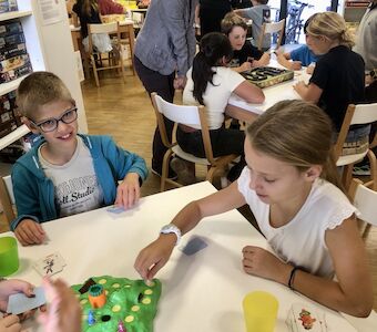 Drei Kinder spielen an einem Tisch das Spiel "Lotti Karotti".