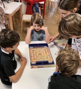 Vier Kinder spielen an einem Tisch das Spiel Kakerlak.