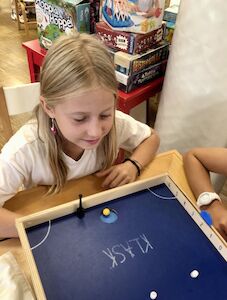 Ein Mädchen spielt ein Geschicklichkeitsspiel und lächelt dabei.