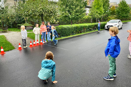 Ein paar Kinder testen ihre Reaktionszeit und Bremsgeschwindigkeit auf einem nassen Asphalt aus.