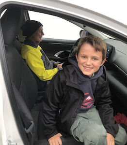 Ein Bub lächelt beim Aussteigen aus dem Auto während der Aktion "Hallo Auto".