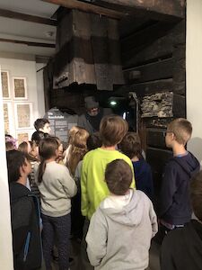 Kinder hören bei der Führung im Volkskundemuseum aufmerksam zu.