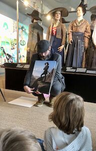 Der Mann, der die Führung macht, hält ein Bild vom Erzherzog Johann in der Hand und die Kinder schauen zu.