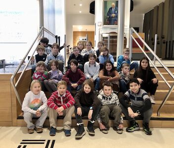 Die Sonnen-Klasse posiert für ein Klassenfoto im Museum auf einer Stiege.