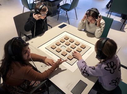 Beim Melodienmemory sitzen 4 Kinder und spielen miteinander.