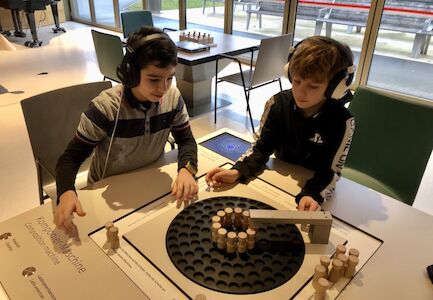 Zwei Buben probieren sich an der Komponiermaschine und haben dafür Kopfhörer auf.