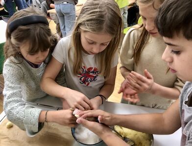 Vier Kinder stehen an einem Tisch und formen Kekse.