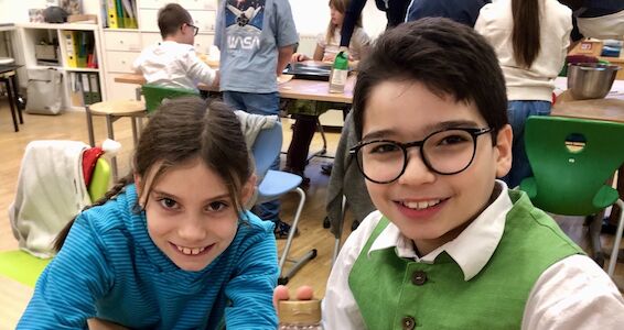 Zwei Kinder lächeln fröhlich in die Kamera.