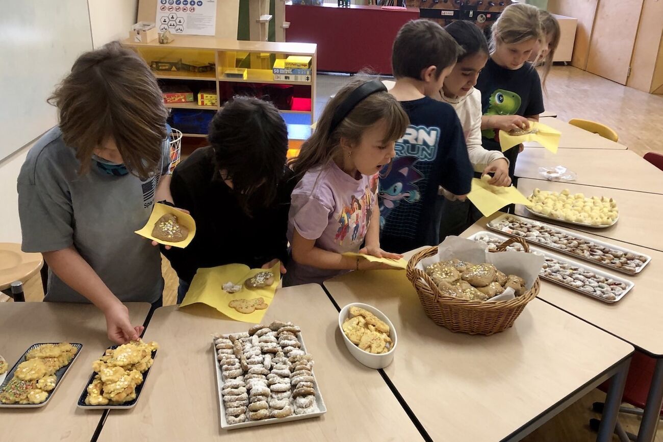 Mehrere Kinder stellen sich beim selbstgemachten Keksbuffet an und bedienen sich an ihren Köstlichkeiten.