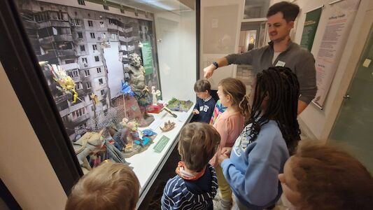 Ein paar Kinder betrachten in einer Vitrine die Ausstellungsgegenstände.