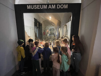 Eine kunstvoll gestaltete Krippe wird von einer Kindergruppe bestaunt.