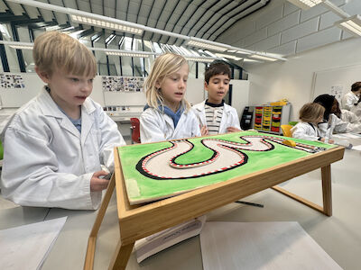 Drei Buben spielen ein Magnetspiel, das einem Autorennen ähnelt.