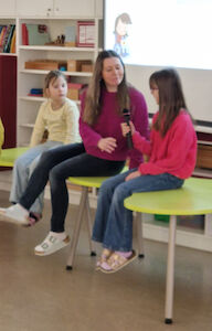 Das Mikrofon wird von einer Schülerin an eine Lehrerin während der Podiumsdiskussion weitergereicht.