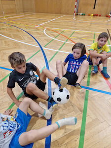 Ein Fußball wird nur mit Füßen von einer Kindergruppe weitergegeben.