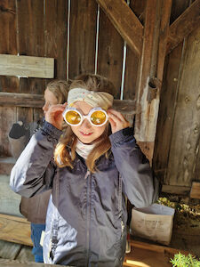 Ein Mädchen probiert eine "Insekten-Brille" aus und hält sie sich an die Augen.