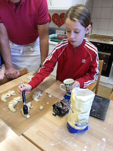 Ein Mädchen bestreicht das Backgut mit einem Pinsel und Eigelb.