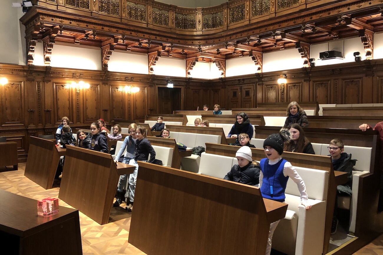 Kinder der Sonnen-Klasse sitzen im Gemeinderatssaal des Grazer Rathaus.