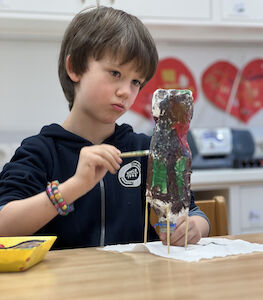 Ein Bub malt mit Akribie seine Rakete an.