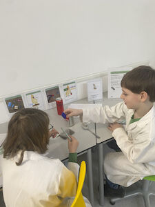 Zwei Kinder experimentieren an einer Station, wo es um magnetische Metalle geht.