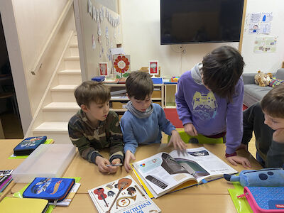 Eine Kindergruppe informiert sich in Büchern über Musikinstrumente etc.