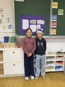 Ein Kinderpaar präsentiert vor der Tafel stehend etwas über das Orchester.