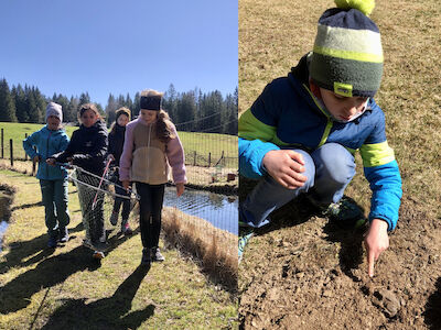 Links geht eine kleine Kindergruppe neben einem Teich mit einem Fischernetz (inkl. Fisch) stolz der Kamera entgegen. Rechts zeigt ein Kind auf eine Erdkröte am Boden.