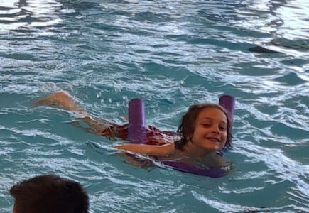 Beim Schwimmen in der Auster wird ein Bub von einer Schwimmnudel unterstützt.