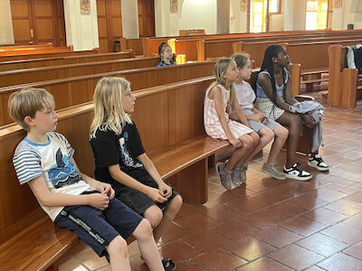 Locker aufgeteilt sitzende Kinder in den Kirchenbänken der Salvatorkirche.