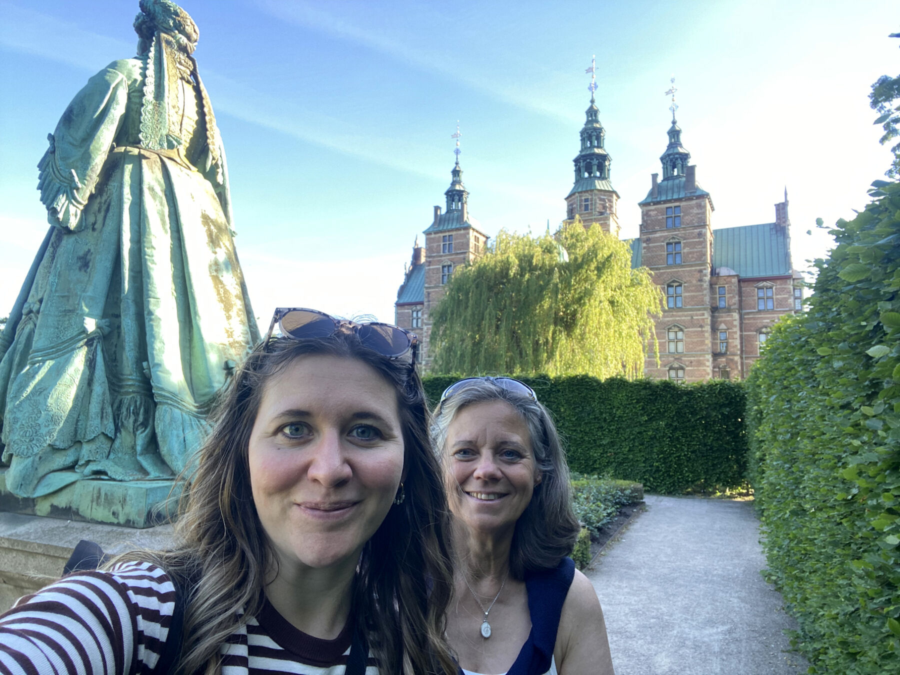 Selfie der beiden Lehrerinnen vor einem Bach und einer Statue.